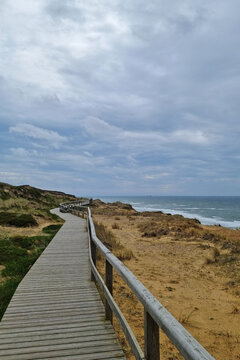 Coastal Boardwalk Overlooking Sandy Beach Under Cloudy Sky