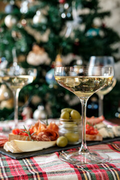 Christmas Holiday Celebration With Champagne Glasses And Charcuterie Board By A Decorated Tree