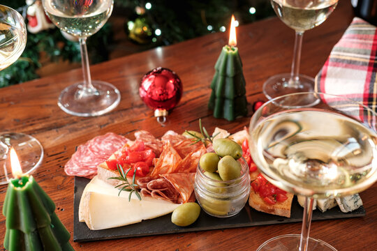Festive Christmas Charcuterie Board With Wine Glasses Near Decorated Tree For Holiday Gathering