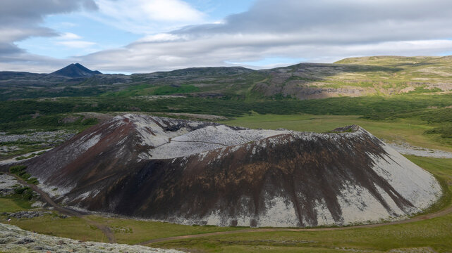 A scenic view of Grabr&oacute;karfell volcanic crater surrounded by rugged lava terrain and green vegetation near Grabrok in West Iceland.