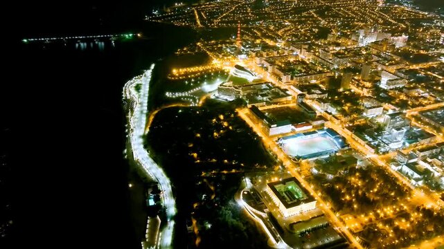 Ufa, Russia. Aerial night panorama over the city center, the illuminated Salavat Yulaev Monument and the glowing ribbon of the Belaya River cutting through the urban grid. Drone footage