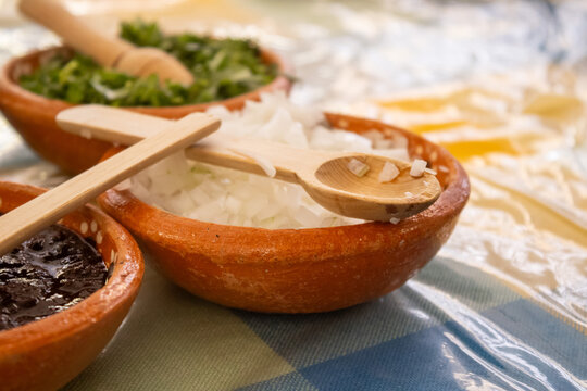 Chopped onion in traditional Mexican clay bowl with wooden spoon