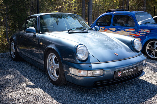 Djurhamn, Sweden - May 10, 2026: Metallic blue Porsche 911 Carrera 964 parked beside a flame painted Volkswagen Beetle hot rod