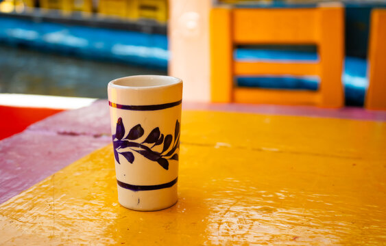 Traditional Mexican ceramic tequila shot glass on wooden table aboard a trajinera