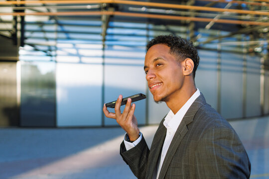 Voice assistant technology, young mixed race businessman using smartphone