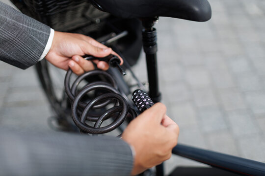 businessman locking bicycle with combination lock outdoors