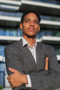 Confident young businessman stands outdoors near modern building