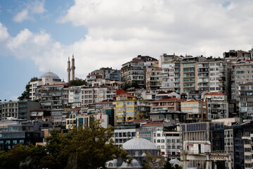 Fototapeta premium Wide view of dense residential buildings and mosque minarets located on a hill in Istanbul. Classic urban turkish landscape representing travel destination and oriental architecture concept.