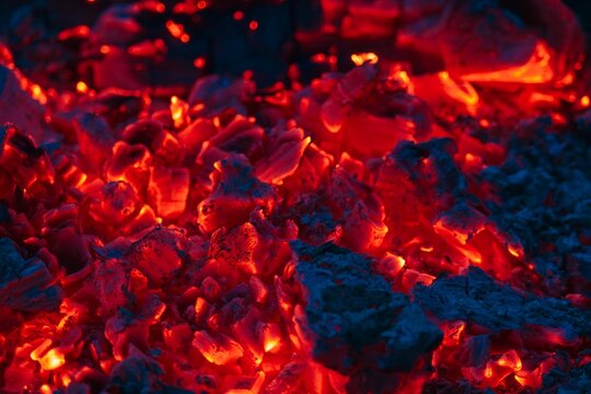 Glowing red embers burning coals with ash close up macro background