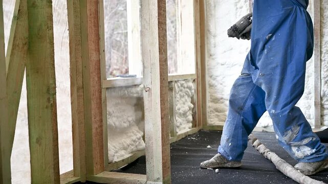 Insulation contractor applies foam to interior wall during building process. Thick expanding layer provides thermal protection, sound dampening, and air sealing