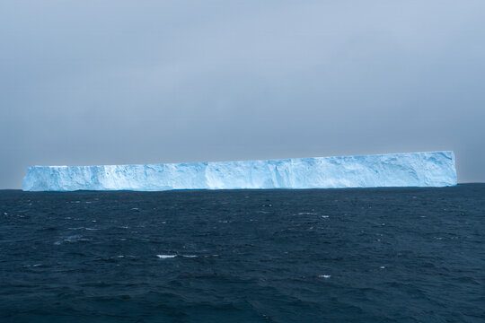 Antarctica: enormous blue tabular Iceberg floating between Antarctic Peninsula and Drake Passage.