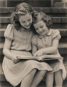 Two 1940s sisters reading a book together on steps