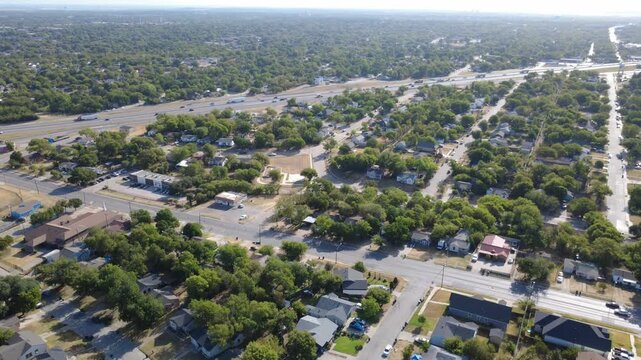 Suburban residential blocks border East Berry Street across Historic Southside. Mature shade trees frame local thoroughfares leading toward distant expressway lanes, Fort Worth, Texas