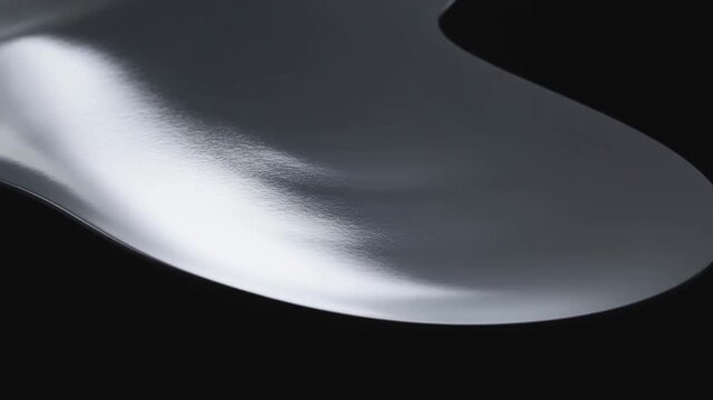 Reflective silver metallic form shifts orientation against a dark black background