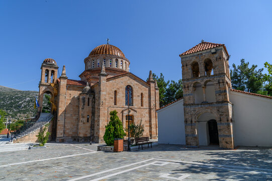 Church of the Transfiguration of the Savior in Vilia, copper dome and old stone bell tower on the paved village square, Greece
