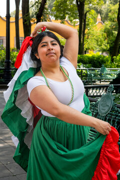 Mexican woman in traditional folkloric dress posing with skirt raised outdoors