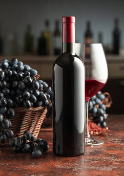 Bottle and glass of red wine with grapes on a vintage table.