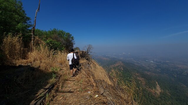 Hikers walking along a narrow mountain trail overlooking the Western Ghats in Maharashtra India