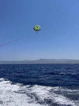 Two people parasailing in the blue sky over the sea, view from the boat