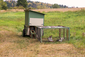 Mobile chicken coop trailer with wire run enclosure standing on green pasture in countryside concept of organic free range farming © Jana Krizova