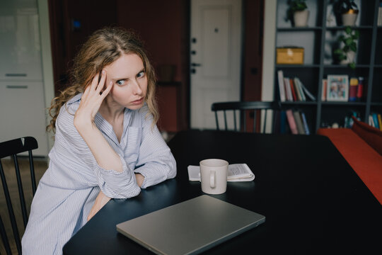 Woman taking a break beside a closed laptop while feeling tired from remote work at home