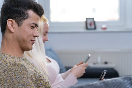 Young adult couple ignoring each other using smartphones