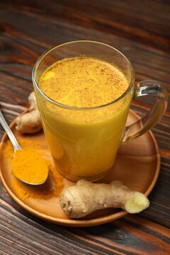 Golden milk turmeric latte and ingredients on wooden table, closeup