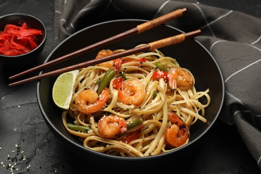 Delicious wok with shrimps served on black table, closeup
