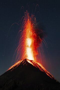 Glowing lava and smoke spitting volcano, volcanic eruption at night, Volcan de Fuego, Guatemala