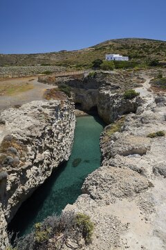 Rocky landscape with clear water and small white house under blue sky, volcanic island, island, Milos, Cyclades, Greek Islands, Greece