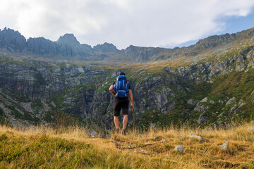 Fototapeta premium Hiker with Backpack Facing Steep Rocky Mountain Range