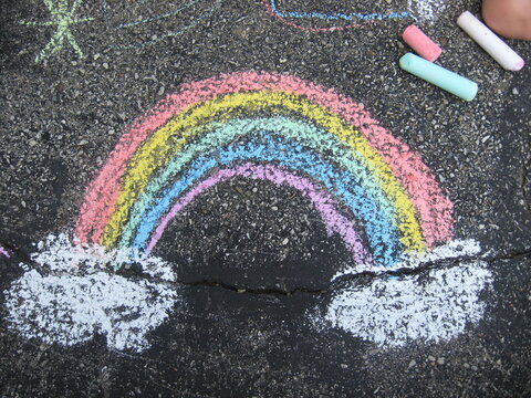 colorful sidewalk chalk rainbow drawing on dark pavement