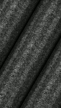 Seamless turning motion of Italian charcoal gray herringbone wool fabric rolls highlighting rich V shape woven pattern and winter outerwear textile