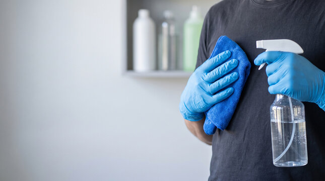 Close Up of Janitor Hands in Blue Nitrile Gloves Holding Spray Bottle and Microfiber Cloth, Commercial Housekeeping and Office Cleaning Service Concept with Left Copy Space