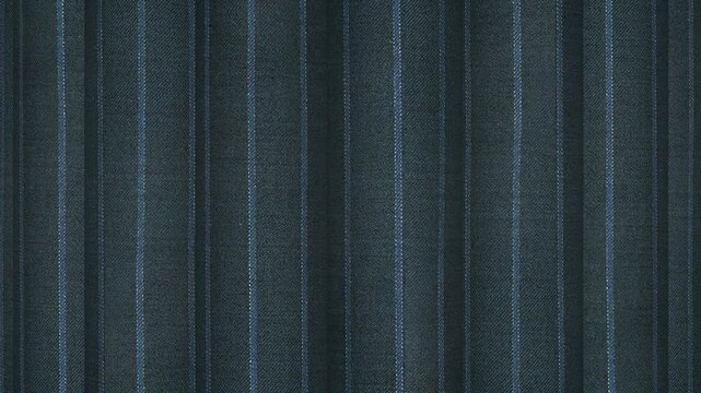 Turning rolls of Italian dark teal gray pinstripe wool fabric displaying unique cool tone hues and sophisticated business apparel weave structure
