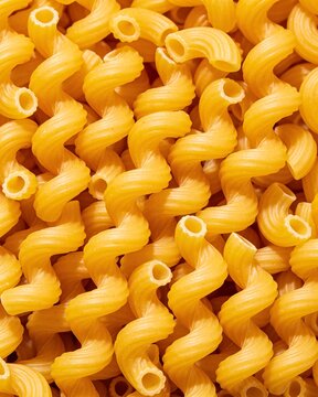 Close-up of uncooked golden curly pasta with spiral shapes and ridged texture.