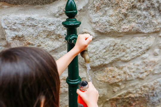 Child Getting Fresh Water from a Public Fountain on a Hot European Summer Day
