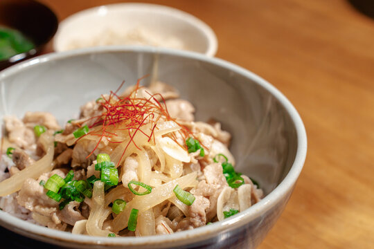 豚肉と玉ねぎがたっぷり盛られた豚丼のクローズアップ。料理のレシピや詳細説明に。