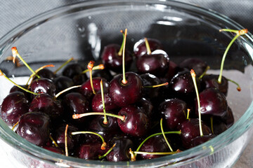 Close-up of juicy ripe cherries with green stems ready to eat, with copy space for text. Detailed food shot of sweet red berries. © Edita