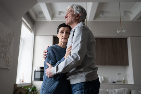 Tired sad mature husband and wife in grief embracing hugging, man comforts wife, holding close. Family crisis, reconciliation after argument, bad news, incurable illness, depression, emotional support