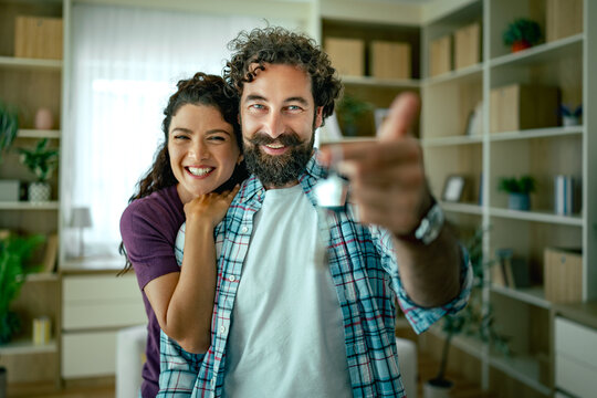 Happy couple holding new house keys celebrating move into their cozy home