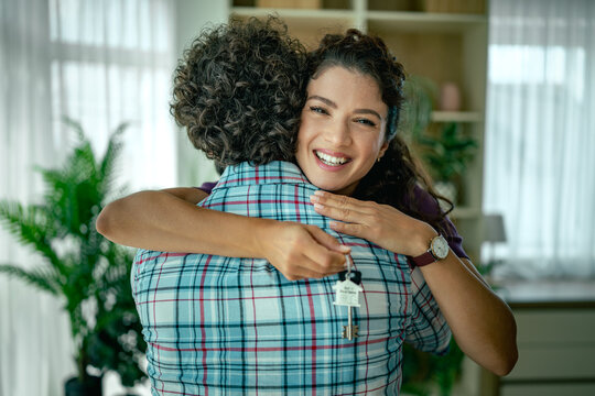 Happy couple hugging as woman holds house keys after buying new home