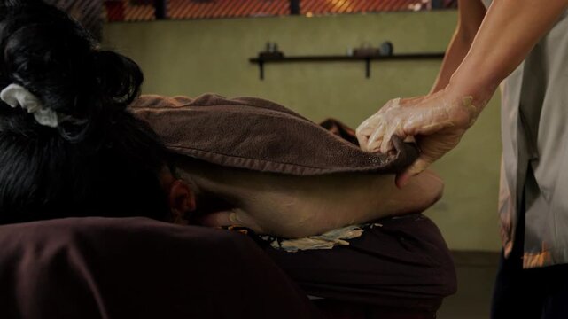 Masseuse applying body scrub during spa massage treatment