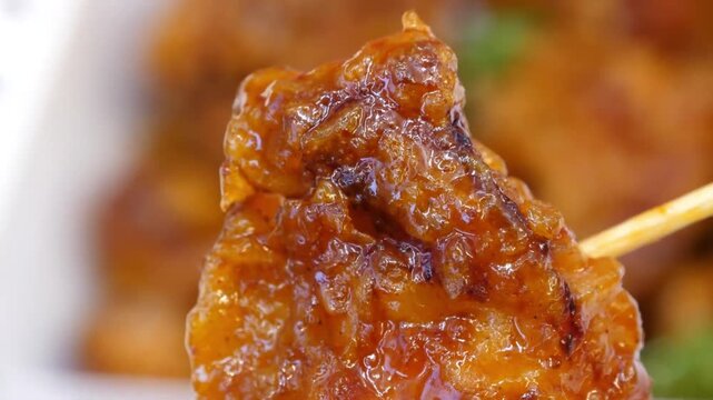 A macro, slow-motion shot detailing a single crispy fried chicken wing dripping with a glistening, vibrant orange buffalo hot sauce. The shot highlights the glossy, sticky texture of the glaze over a 