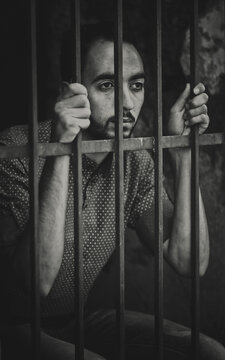 Young man behind metal bars in black and white