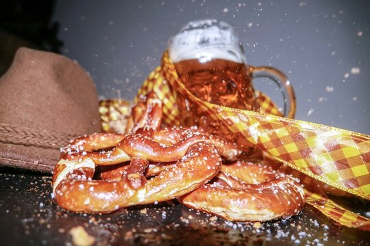 Traditional Bavarian pretzels and a beer stein with a felt alpine hat, featuring salty crust and frothy foam for beer festival celebrations