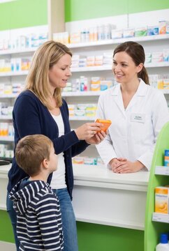 Woman with child consulting pharmacist about medication in a pharmacy, shelves filled with various health products and medications in the background