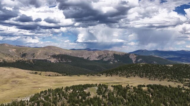 Aerial of mountainous forest and meadow under dramatic clouds in Colorado near Keystone in summer