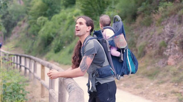 Father carrying his daughter in backpack carrier enjoying a nature trail
