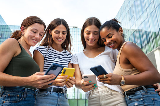 Diverse friends enjoying social media on smartphones outdoors